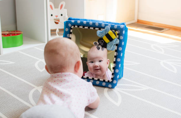 Baby looking in the mirror during tummy time. Baby care. Baby development